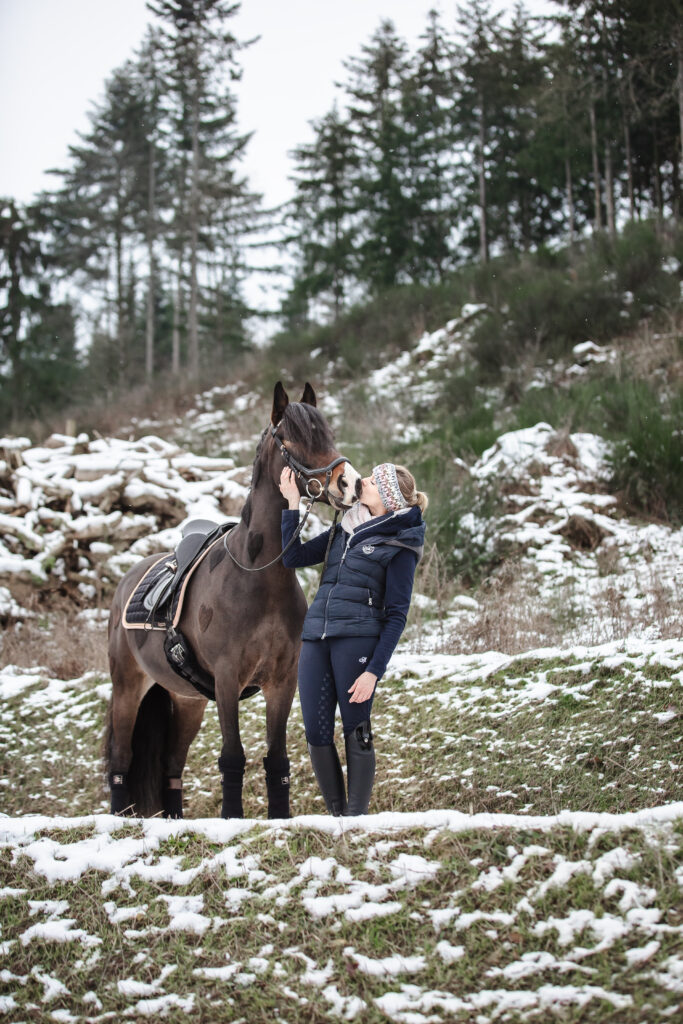 Frau küsst Pony bei Pferdefotoshooting im Schnee mit Coralie Duda Fotografie im Wetteraukreis