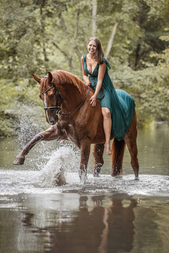 Frau reitet Pferd durch Wasser bei Fotoshooting mit Coralie Duda Fotografie im Wetteraukreis